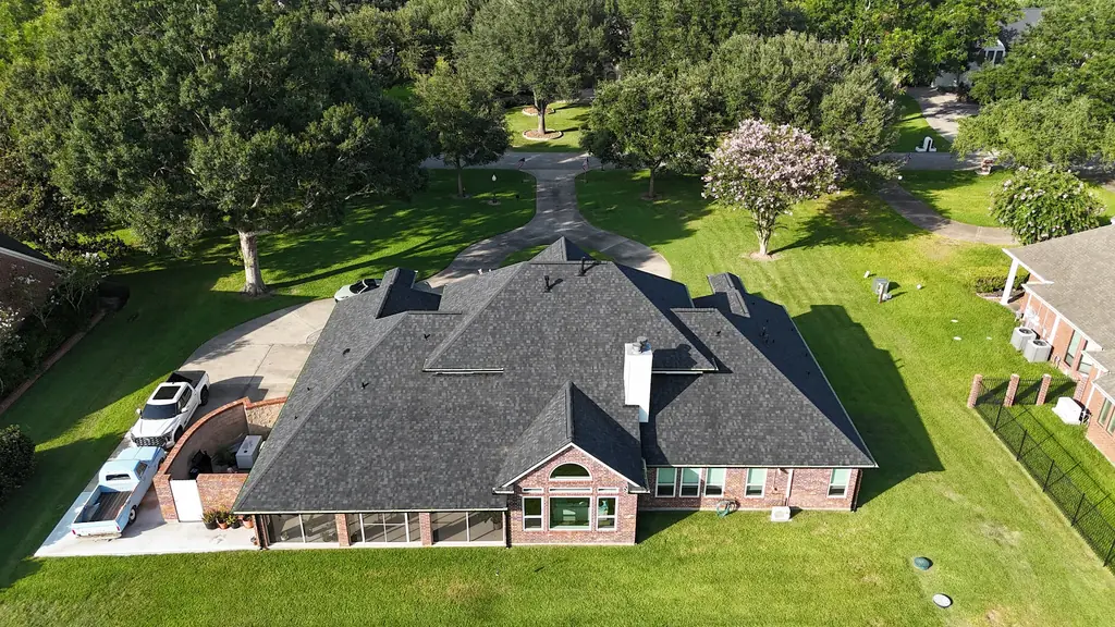 Aerial view of a large brick home with a new dark architectural shingle roof