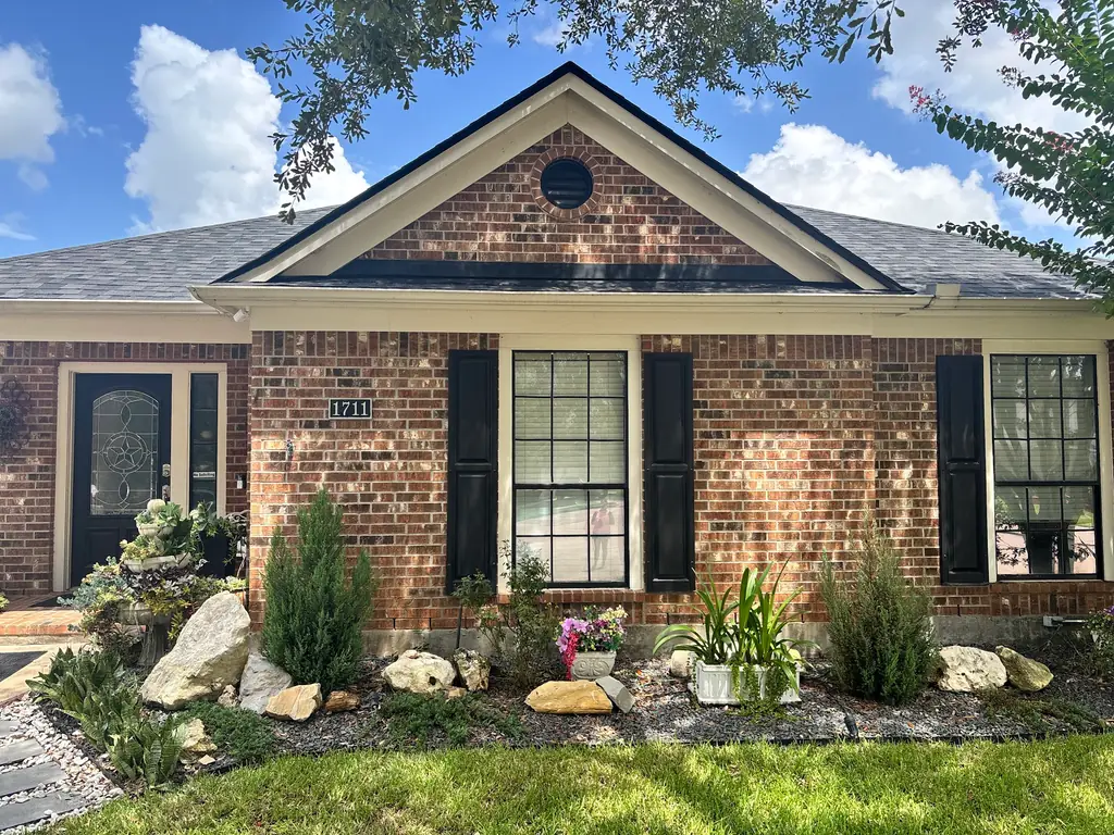 Ground level view of a Richmond, Texas brick home with a newly finished roofline