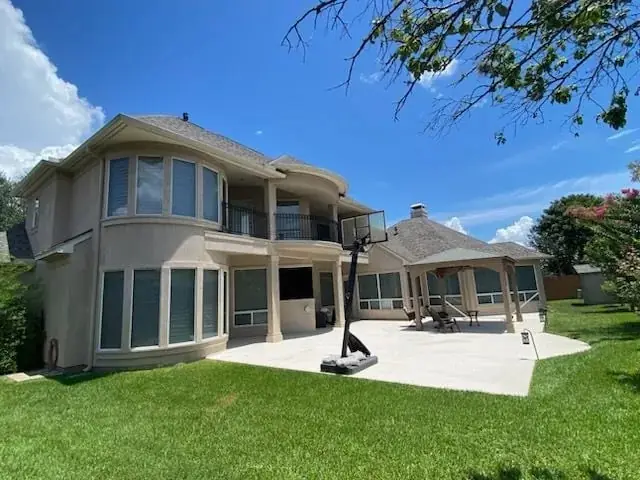Rear exterior of a two storey stucco home with a new roof, patio and pool area