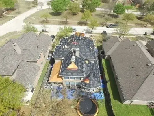 Aerial view of a roof mid installation with felt underlayment down and partial shingle courses laid